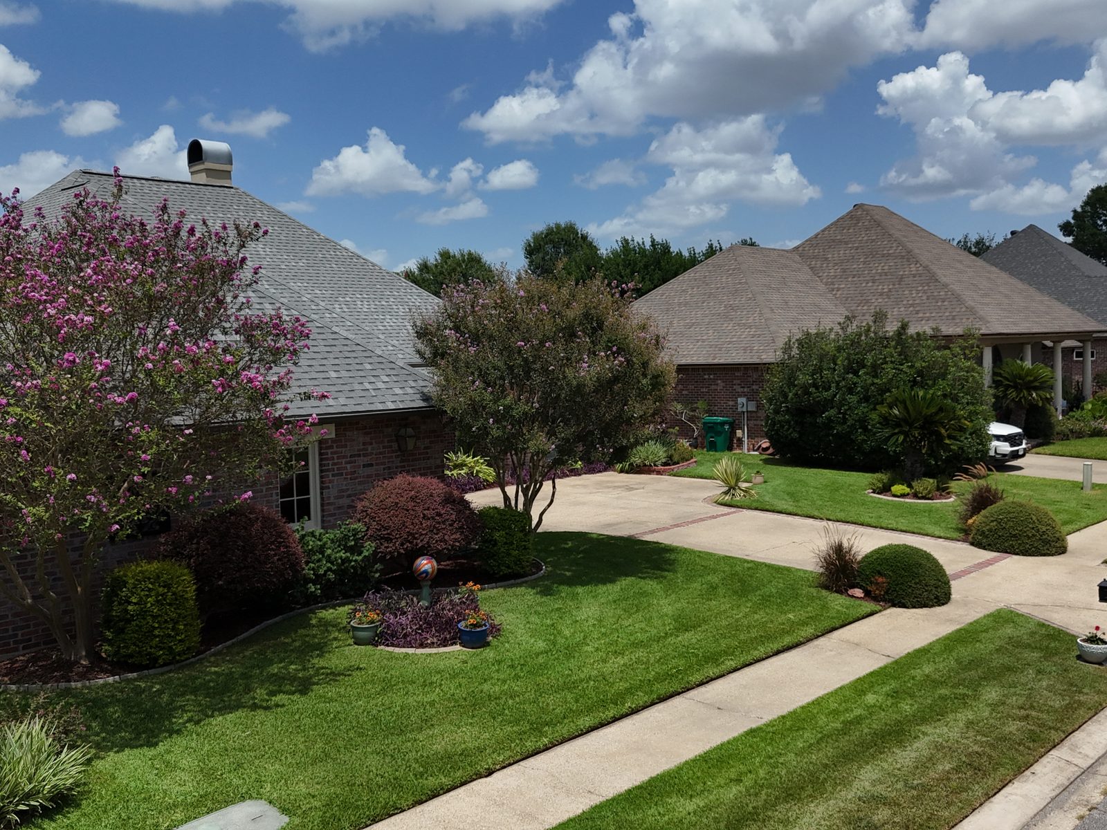 Aerial view of a manicured front yard with crisp edging and flowering crepe myrtles