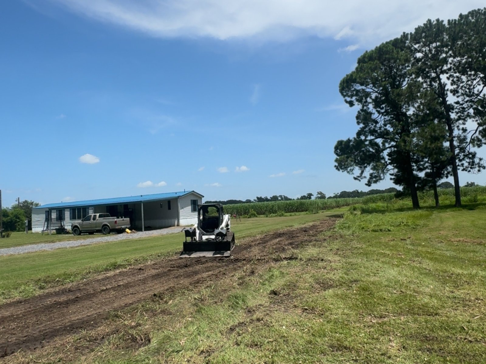 Skid steer clearing a path on a property job